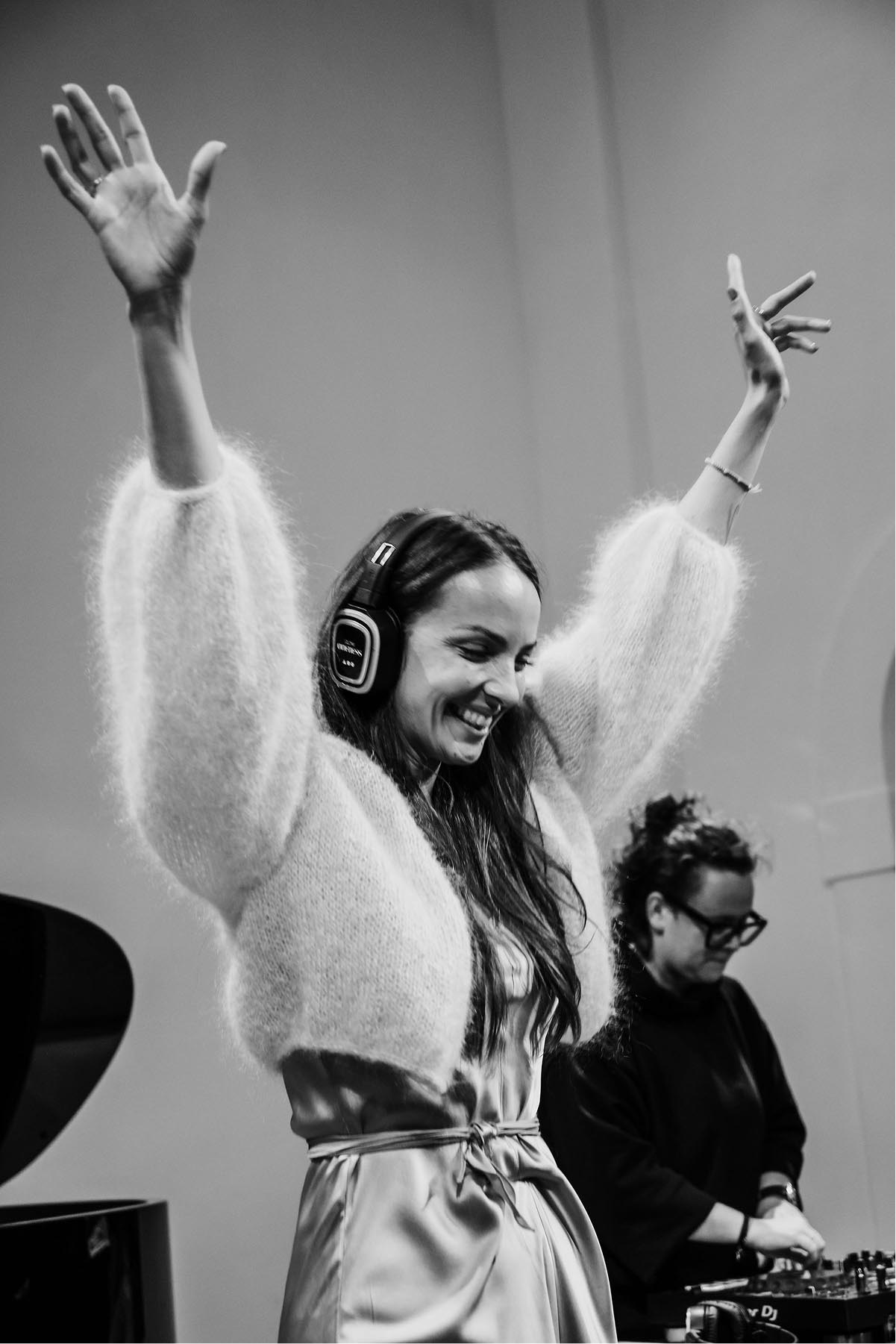 Lucie Vonchitzki se sluchátky a rukama nad hlavou u DJ pultu