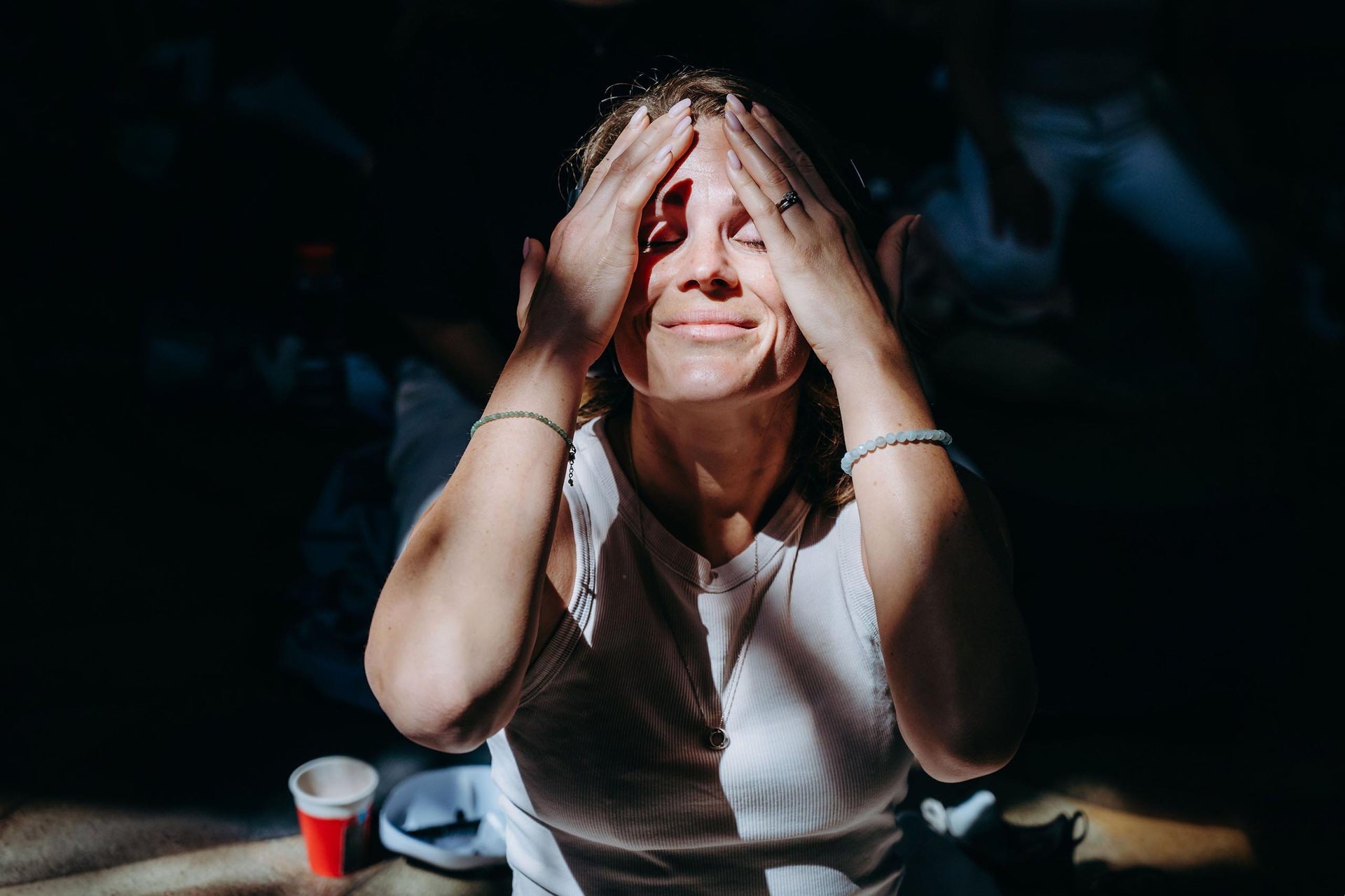 Usměvavá žena s rukama na čele v pruhu slunečního světla