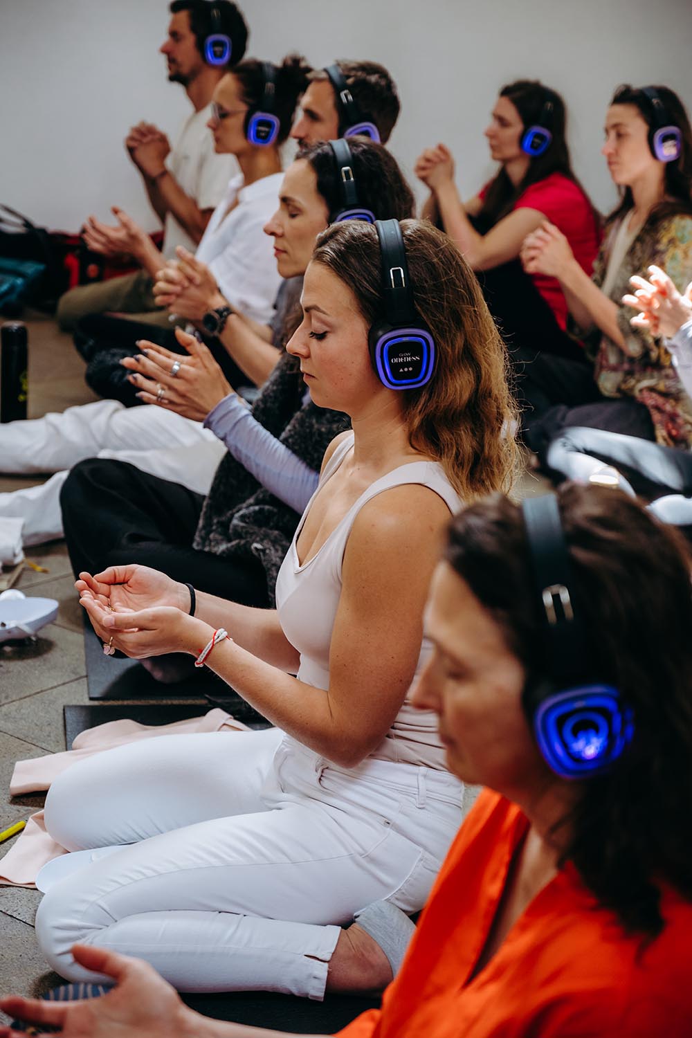 Účastnice v meditaci se svítícími sluchátky